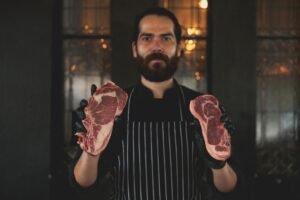 bearded man holding slices of raw meat